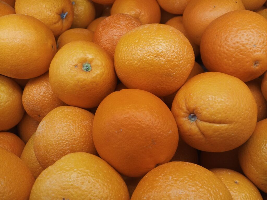 A vibrant collection of fresh oranges stacked closely together, showcasing their bright color.